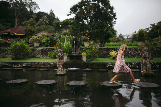 Caucasian girl in watermelon dress exploring water palace in Bal