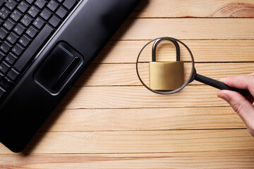 privacy data protection. above view for a black laptop and golden padlock over wooden desk. cyberspace safety technology concept