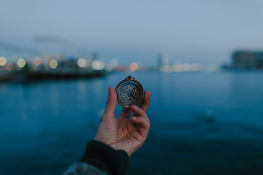 hand holding a compass from a dock of barcelona