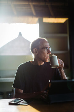 Mature man in his 60's working and traveling with tablet in trop