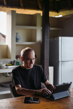 Mature man in his 60's working and traveling with tablet in trop