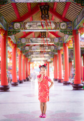 cute little asian girl in chinese traditional dress smiling and standing in the temple.Happy chinese new year concept.