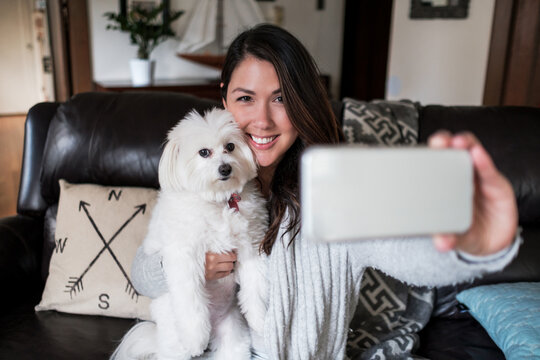 Beautiful woman taking a selfie with her dog at home