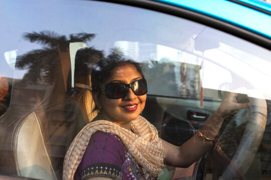 Young woman holding steering of a car and looking at camera