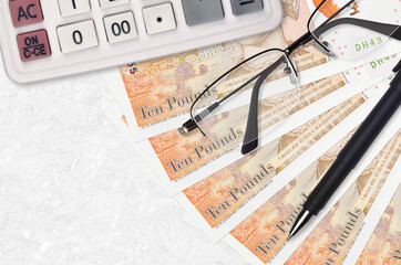 10 British pounds bills fan and calculator with glasses and pen. Business loan or tax payment...