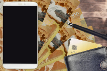 100 Canadian dollars bills and smartphone with purse and credit card. E-payments or e-commerce...