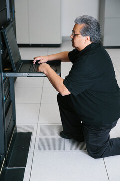 IT computer programmer working on datacenter servers on laptop