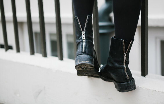 Detail of woman wearing cool zip up boots standing on a railing