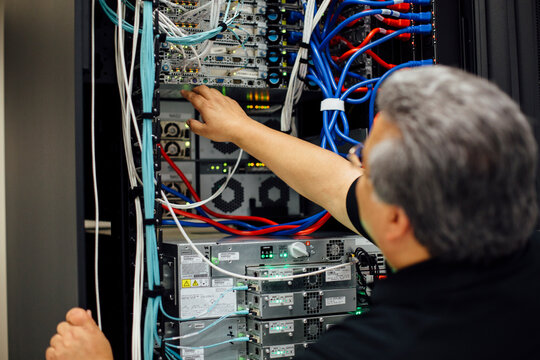 Computer expert working with cables on back of server