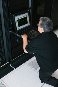 IT programmer working on computer servers on laptop