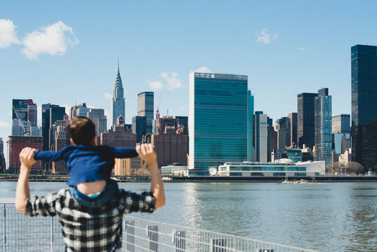 Dad holding kid on shoulders in front of NYC skyline
