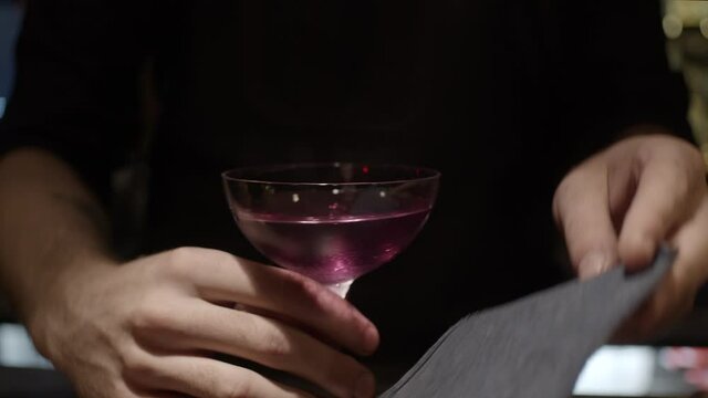 Bartender moves cocktail to camera, slow motion