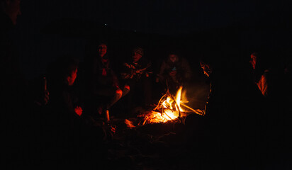 Five friends enjoying themselves around a camp fire.