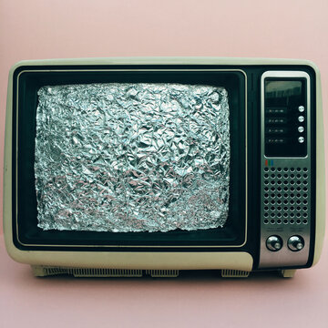 Old television with screen covered with tin foil
