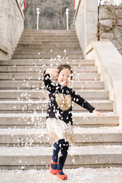 Adorable girl playing with cherry blossom petals