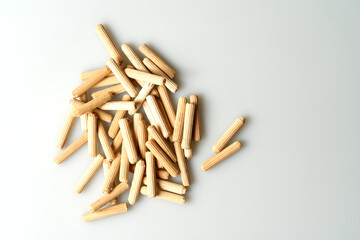 pile of wooden dowels on white table, carpentry connectors, top view