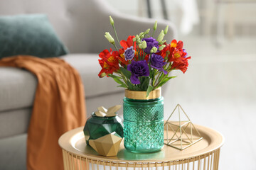 Glass vase with fresh flowers on table in living room