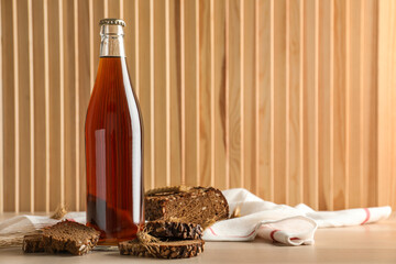 Bottle of delicious fresh kvass, spikelets and bread on wooden table. Space for text