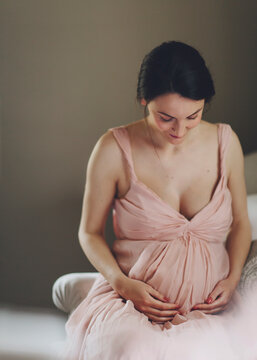 Sweet sneek peak: mother to be embracing her pregnant belly and smiling