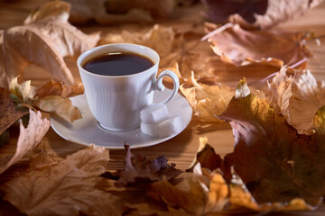 Cup of coffee on the table with autumn leaves