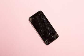 Smartphone with cracked screen over pink background