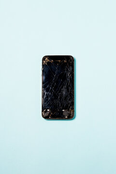 Smartphone with cracked screen over blue background