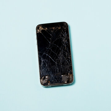Smartphone with cracked screen over blue background