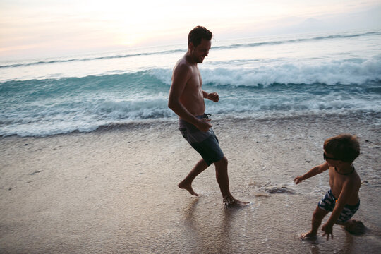 Young dad and son enjoying tropical Bali beach together at sunse