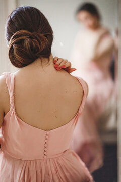 Rear sight of young woman wearing pale pink dress and a chignon hairstyle