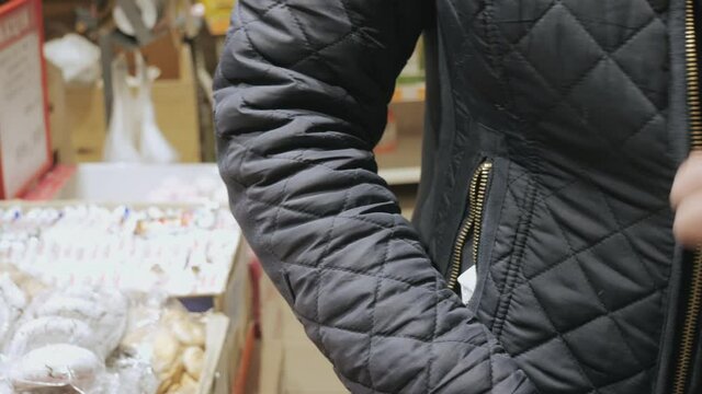 A woman steals food from a supermarket. Thief in the store. Shoplifting. Coronavirus, covid-19 economic crisis