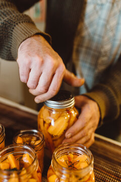 Man tightening top of jar of preserved carrots