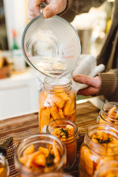 Vinegar being poured into preserved jars of carrots