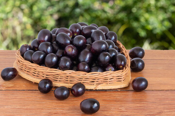 Purple grapes in basket with heart shape on wooden table with blurred background.