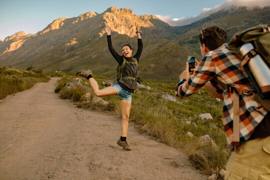 Excited woman on hiking trail being photographed by her boyfrien