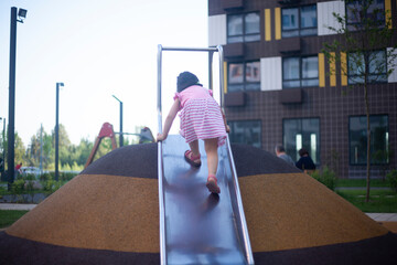 The girl climbs the slide in the playground.
