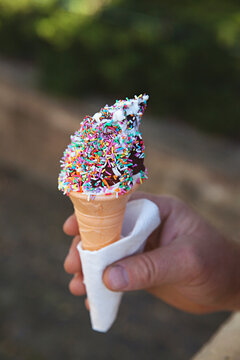 Man holding soft serve ice cream with chocolate and sprinkles