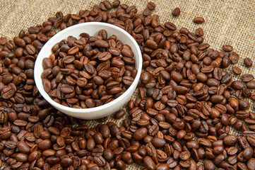 Coffee beans in a white cup on a background of burlap