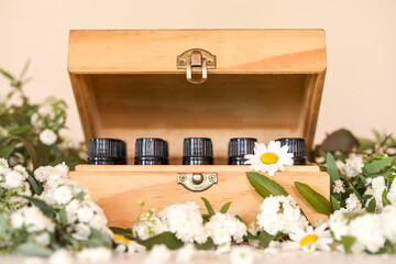Wooden essential oil storage box with bottle caps visible sitting in bed of white flowers. Wellness image featuring chrysanthemums. 
