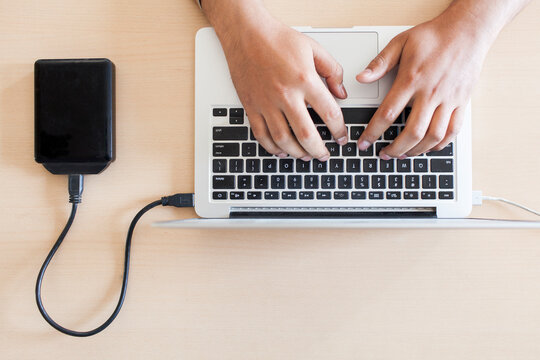 Hands of a man working on a laptop.