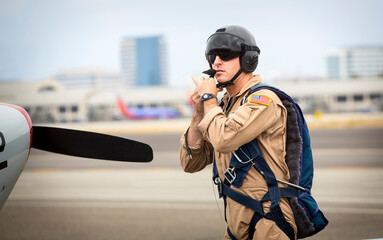 Fighter pilot straping on helmet and goggles while walking near runway toward Marchetti SIAI SF260 fighter airplane © F Armstrong Photo
