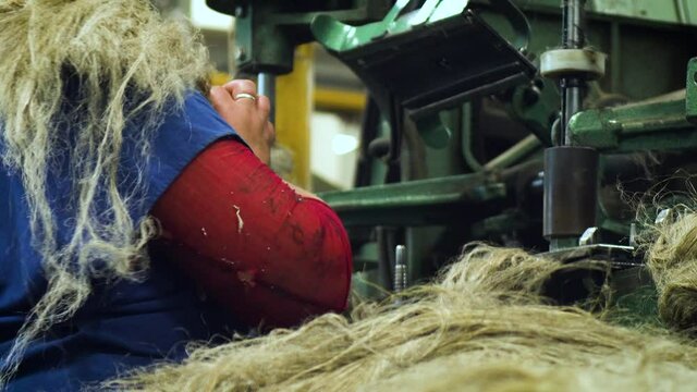 Close-up of a woman prepares wool on the background of a loom.