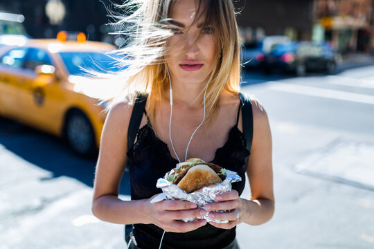 Blonde woman having an hamburger in the streets of NYC