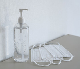 Sanitizing gel and mask in front of the white wall