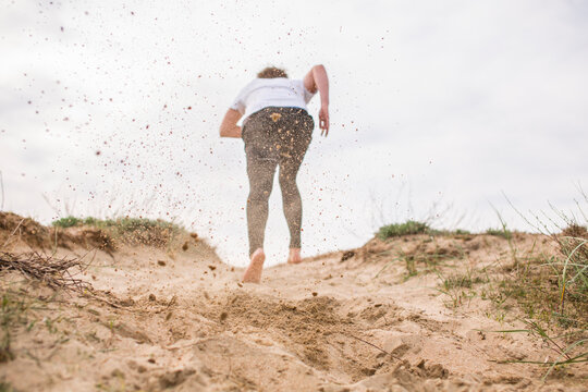 Young man running and flinging sand in the air.