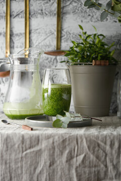 Delicious homemade green detox juice sits in glass on table.