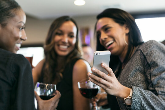 Restaurant: Women Friends Laugh While Looking At Cell Phone