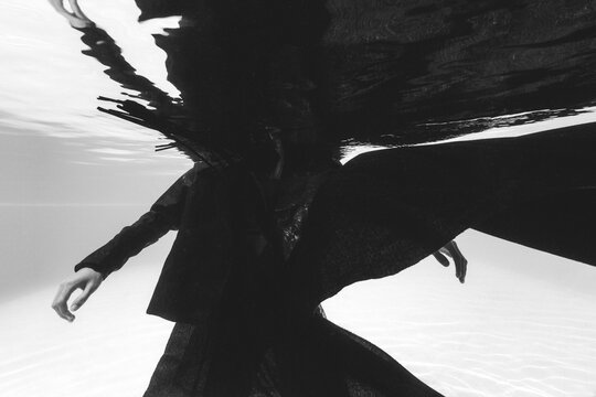 Beautiful man dressed in black floating in the pool