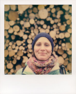 Woman stands in front of a huge pile of wood