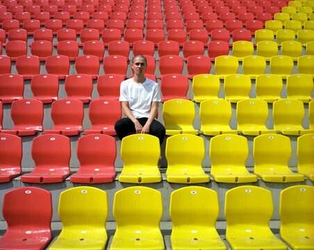 Young man sitting on colourful stadium seats