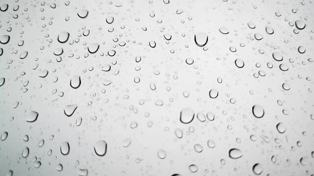 Rainwater drops Falling Down On the Window Glass, Rain Drops On The Windows Glass, Macro shot of water droplets falling.

